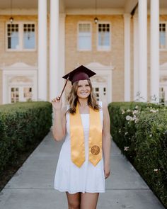 a woman wearing a graduation cap and gown posing for a photo in front of a building