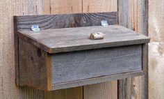 a wooden box with two small rocks on it's side hanging from a wood fence