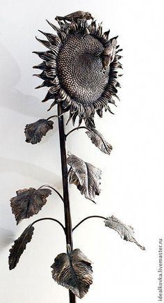 a metal sunflower sculpture sitting on top of a white wall