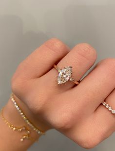 a woman's hand with three different rings on her fingers and one is wearing a diamond ring