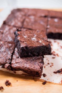 two pieces of chocolate brownie sitting on top of a wooden cutting board