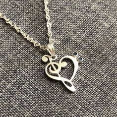 a silver necklace with a musical note in the shape of a heart