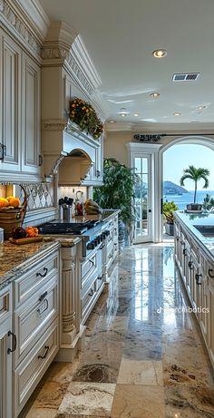 a large kitchen with marble counter tops and white cabinets, along with an ocean view