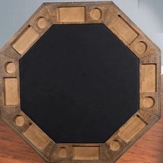 an octagonal wooden frame with holes in the middle on a wood surface, and two smaller circles around it