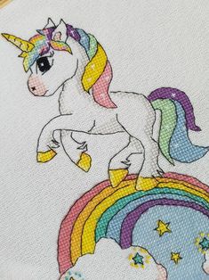 a cross stitch unicorn with rainbows and stars on it's back is shown