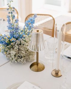 the table is set with blue and white flowers in glass vases, candlesticks, and napkins