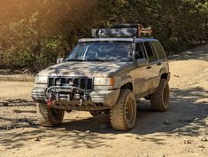 a jeep is parked on the side of a dirt road with trees in the background