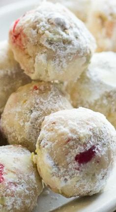 a white plate topped with powdered sugar covered donuts and cranberry sauce