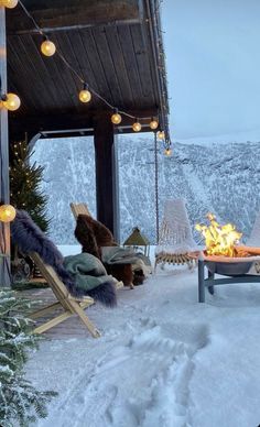 a porch covered in snow next to a fire pit with chairs and lights on it