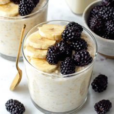 two glasses filled with oatmeal topped with bananas and blackberries