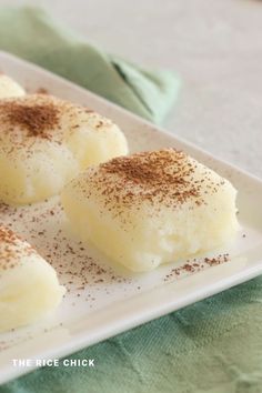 three desserts on a white plate topped with powdered sugar and cinnamon sprinkles