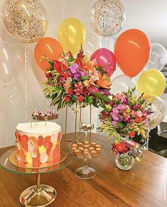 a table topped with a cake and lots of balloons