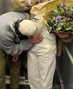 three people standing on an escalator with flowers in their hands and one person holding a bouquet