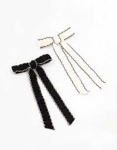 three pieces of black and white hair ties on a white surface with one tied up to the side