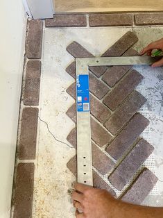 a man is measuring the width of a tile floor with a tape measure ruler on it