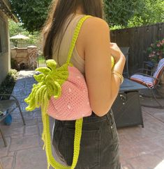 a woman carrying a pink crocheted bag with a banana attached to it's back