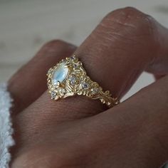 Step into a realm of ethereal beauty with our enchanting "Moonstone Moon Diamond" ring. This ring features a magical natural moonstone with a blue sheen when light reflects on it. Handcrafted in your choice of 14K and 18K gold. Only one available. All orders come in our Tippy Taste ring box. This ring is handmade and designed in NYC. 14K or 18K solid gold Natural oval moonstone. 6*4mm 12 Natural round diamonds. SI clarity, GH color, 0.11ct total carat weight 1.1mm width, 1.5mm thick band ** Tippy Taste Heirloom Collection is made to order. Please allow 3-4 week turnaround time. Shipping:Domestic: Free shippingInternational: Free shippingAll orders are insured, come with tracking, and with signature requirements. Please review our international shipping. Customization:- Interested in custom Ethereal Gold Moonstone Ring For Gift, Ethereal Gold Moonstone Ring Gift, Celestial Moonstone Ring With Rose Cut Diamonds, Celestial Gold Moonstone Ring, Gold Celestial Moonstone Ring With Rose Cut Diamonds, Gold Moonstone Ring With Moon Phase Detail, Celestial Moonstone Ring For Wedding, Celestial Moonstone Wedding Ring, Ethereal Moonstone Wedding Ring With Rose Cut Diamonds