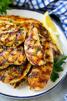 grilled chicken on a plate with lemon wedges and parsley