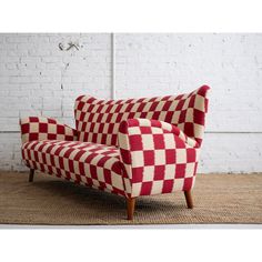 a red and white checkered couch sitting on top of a rug next to a brick wall