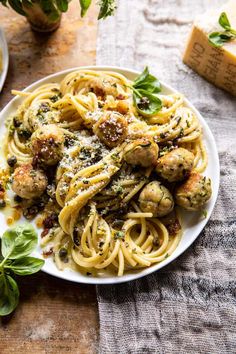 a plate of pasta with meatballs and sauce on it next to some parmesan cheese