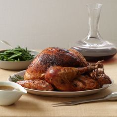 a roasted turkey on a plate with gravy and green beans next to it