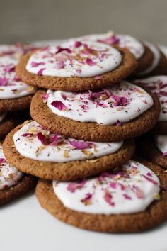 a pile of cookies with white frosting and sprinkles on them sitting on a plate