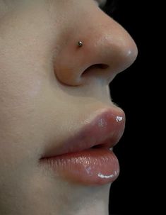 a woman's nose and nose piercings are seen in this close up photo