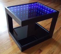 a black table with blue lights on it sitting on a hard wood floor next to a wooden floor