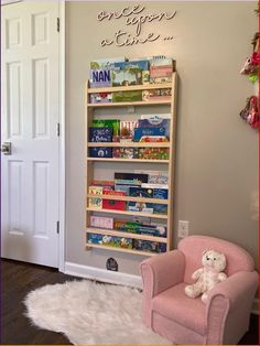 a pink chair sitting in front of a bookshelf filled with children's books