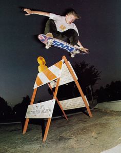 a man flying through the air while riding a skateboard in front of a sign