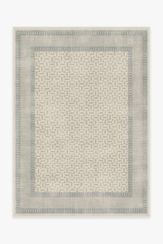 a white rug with blue and grey squares on the bottom, in front of a light gray background