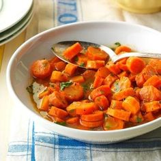 a white bowl filled with carrots on top of a blue and white table cloth