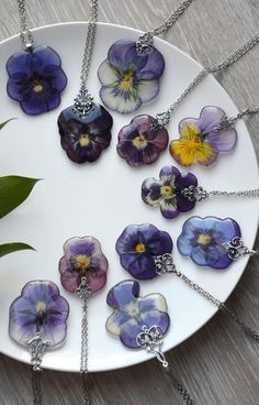 a white plate topped with lots of purple and yellow pansies on chain necklaces