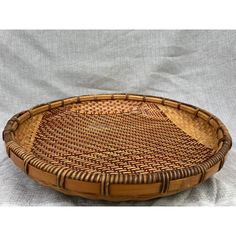 a brown woven basket sitting on top of a white cloth covered tablecloth with an oval design in the center