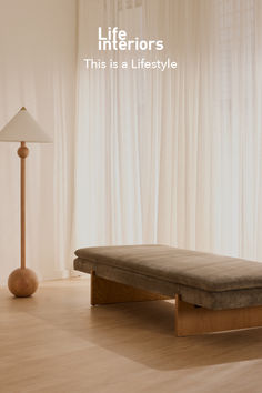 a bed sitting on top of a hard wood floor next to a lamp and window