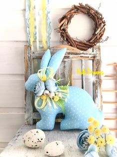 a blue bunny statue sitting on top of a table next to eggs and wreaths