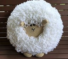 a crocheted sheep sitting on top of a wooden bench