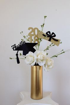 a gold vase filled with white flowers on top of a table