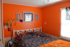 a bedroom with an orange wall and bed