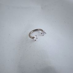 a single diamond ring sitting on top of a white surface with one stone in the middle