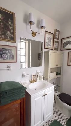 a bathroom with a toilet, sink and pictures on the wall above it's mirror