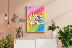 there is no place like home poster on the wall above a white cabinet with potted plants