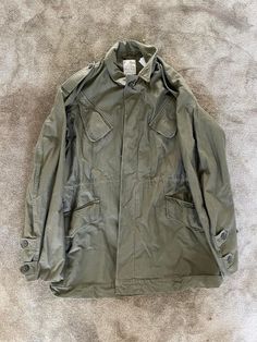 This 80's Military Dutch Field Jacket is perfect for any fashion enthusiast looking to add a touch of khaki to their wardrobe. The jacket, made by Field, features a picture of the outer shell material and is sized according to the provided picture. The jacket is perfect for men who want to add a touch of military style to their clothing collection. The jacket is designed with a regular size type and is available in the color khaki. It is a great addition to any wardrobe and can be paired with a Military Style Khaki Outerwear For Fall, Khaki Military Outerwear For Fall, Vintage Olive Long Sleeve Outerwear, Olive Vintage Long Sleeve Outerwear, Spring Military Style Khaki Parka, Military Style Olive Outerwear With Pockets, Military Olive Outerwear With Pockets, Olive Military Outerwear With Pockets, Olive Military Style Outerwear With Pockets