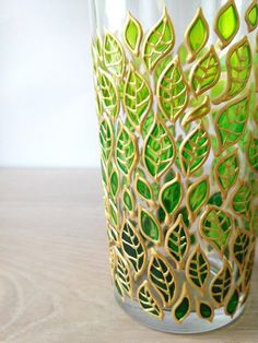 a green and gold vase sitting on top of a wooden table