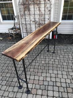 a wooden table sitting on top of a brick sidewalk next to a building with windows