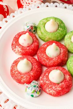 a white plate topped with red and green cookies covered in icing next to candy candies