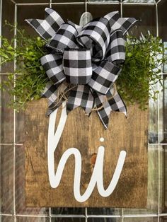 a wooden sign with a black and white checkered bow hanging from it's side