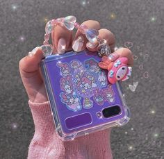 a person holding up a purple phone case with hello kitty on the front and an octopus on the back