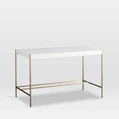 a white table with gold legs and a shelf on the bottom that has two shelves underneath it