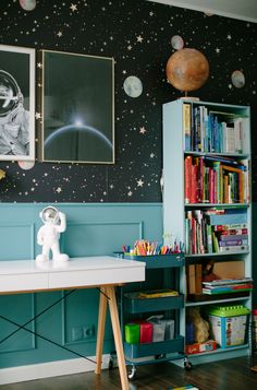 a space themed room with bookshelves, desk and toy astronaut on the wall